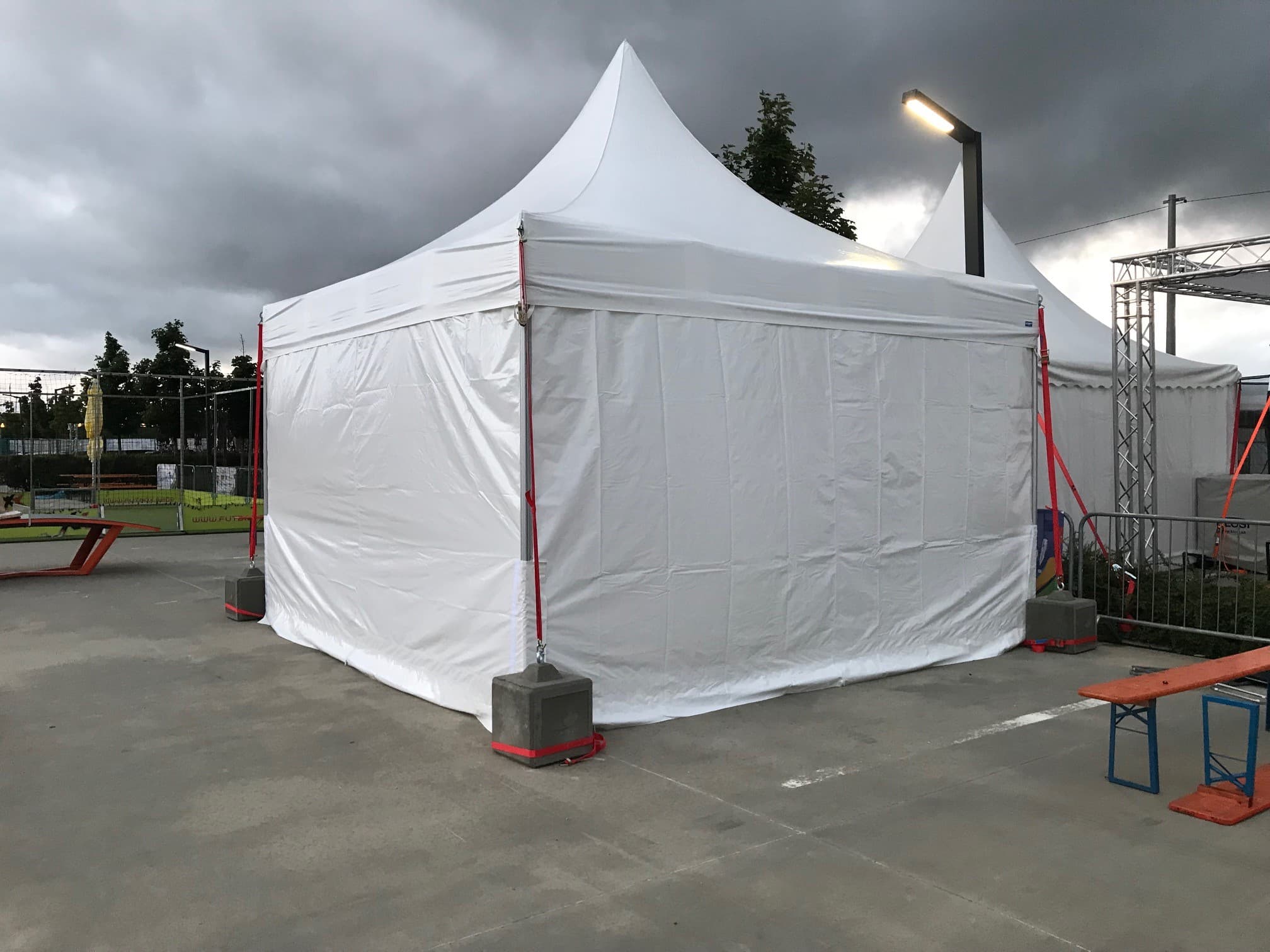 White LP Tent pagoda tents with concrete anchors at an outdoor event venue